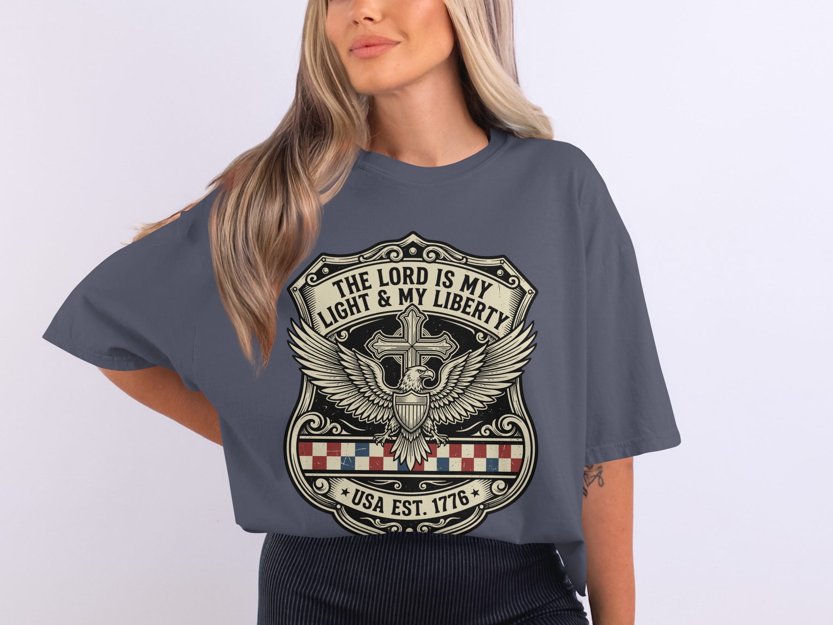 Dark grey t-shirt with a shield design featuring an eagle and the text "THE LORD IS MY LIGHT & MY LIBERTY USA EST. 1776".