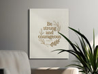Be strong and courageous text on canvas art, with decorative leaf design.