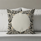 Square decorative pillow with a black and gold floral border on a bed.