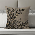 Textured pillow with dark floral and leaf embroidery on a bed.