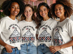 Four women wearing t-shirts with a patriotic design and text "The Rock of Our Nation Is Christ the Lord."