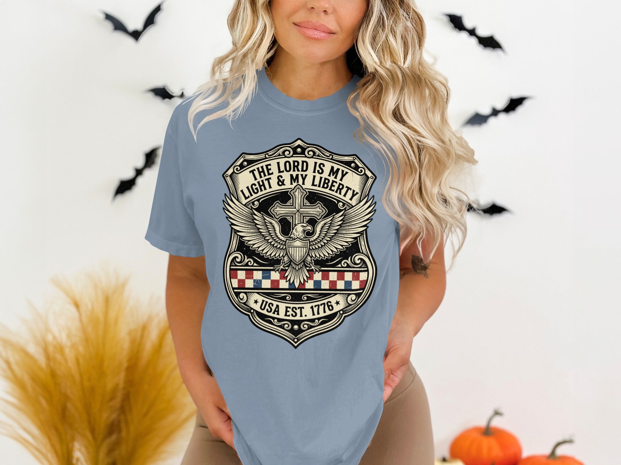 Light blue t-shirt with shield emblem, USA EST 1776, cross, wings, and eagle.