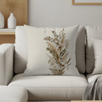 Square decorative pillow with dried floral arrangement design on a cream couch.