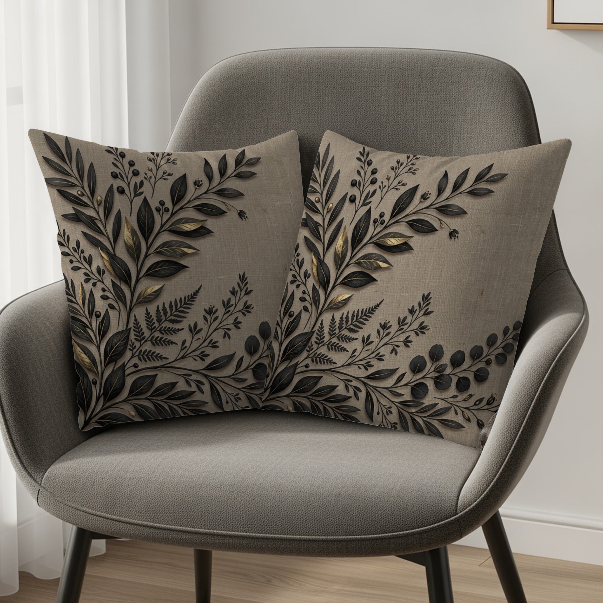 Two decorative throw pillows with botanical leaf designs on a gray chair.