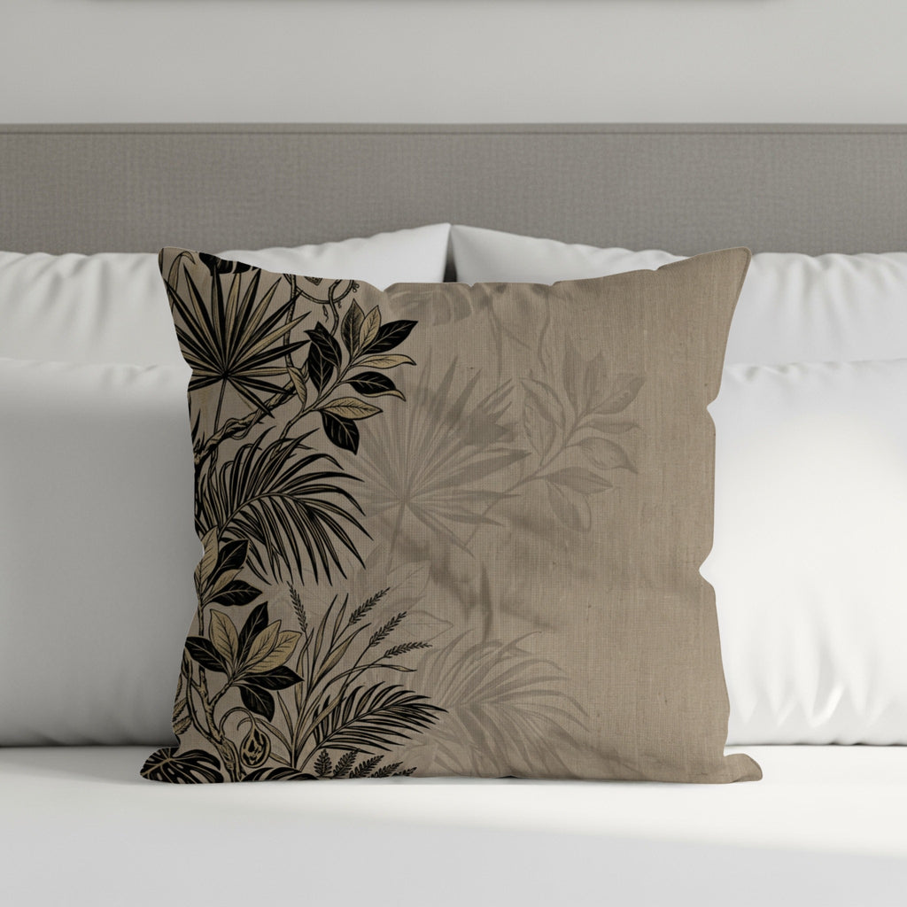Tan throw pillow with black botanical print on a bed.