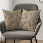 Two decorative throw pillows with a subtle floral and leaf pattern on a chair.