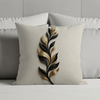 Cream pillow with a black and gold leaf design on a bed.