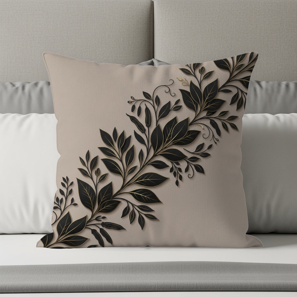 Beige throw pillow with black and gold floral vine design on a bed.