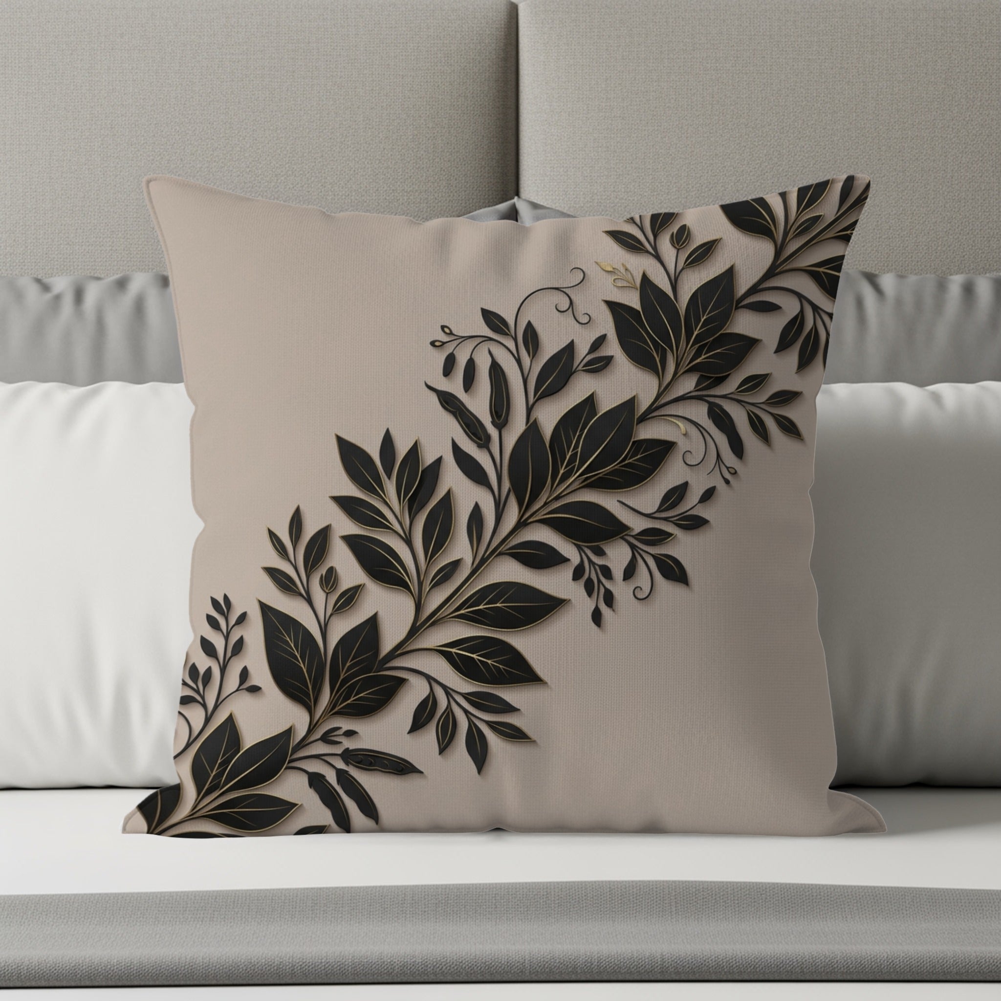 Beige throw pillow with black and gold floral vine design on a bed.