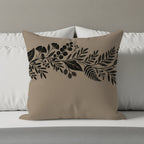 Tan throw pillow with black floral and leaf vine pattern.