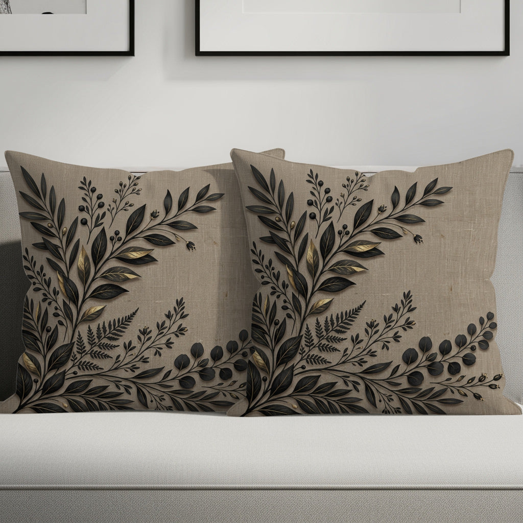 Two decorative linen throw pillows with black and gold botanical leaf design.