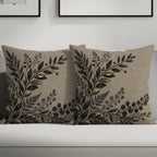 Two decorative linen throw pillows with black and gold botanical leaf design.