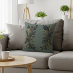 Green throw pillow with gold and dark green floral design on a gray sofa.