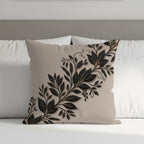 Beige throw pillow with black and gold floral leaf design.