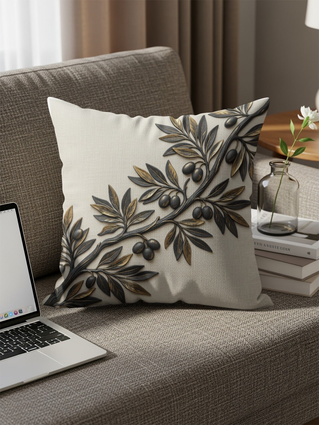 Pillow with embossed olive branch and olives on a couch.