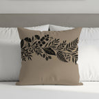 Tan throw pillow with black floral and botanical border design.
