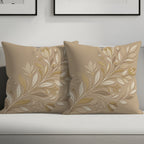 Two tan decorative pillows with cream and gold floral branch pattern.