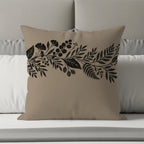 Tan throw pillow with a black and gold botanical floral border design.