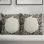 Two square throw pillows with a cream background and dark floral leaf border.