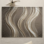Textured blanket with abstract wavy gold and silver stripes and scattered beads.
