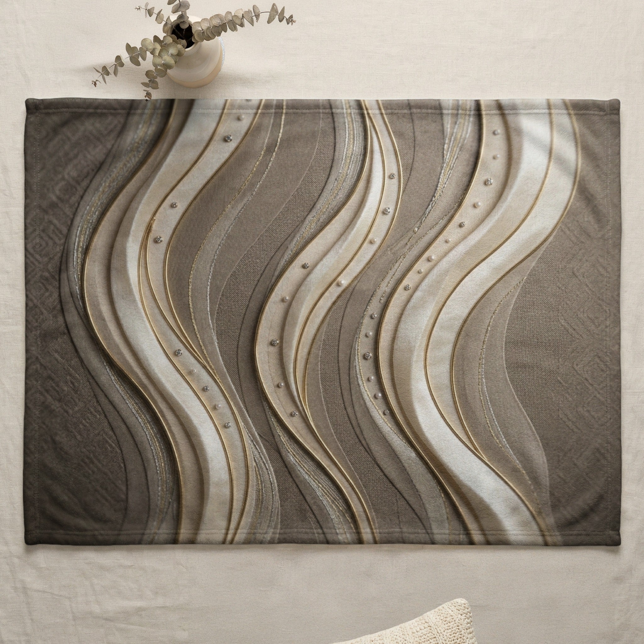 Textured blanket with abstract wavy gold and silver stripes and scattered beads.