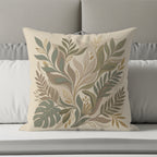 Square decorative pillow with botanical leaf pattern in muted green and beige tones.