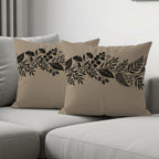 Two beige throw pillows with black and gold floral border patterns.
