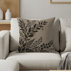 Cushion with dark botanical print on a light textured background.