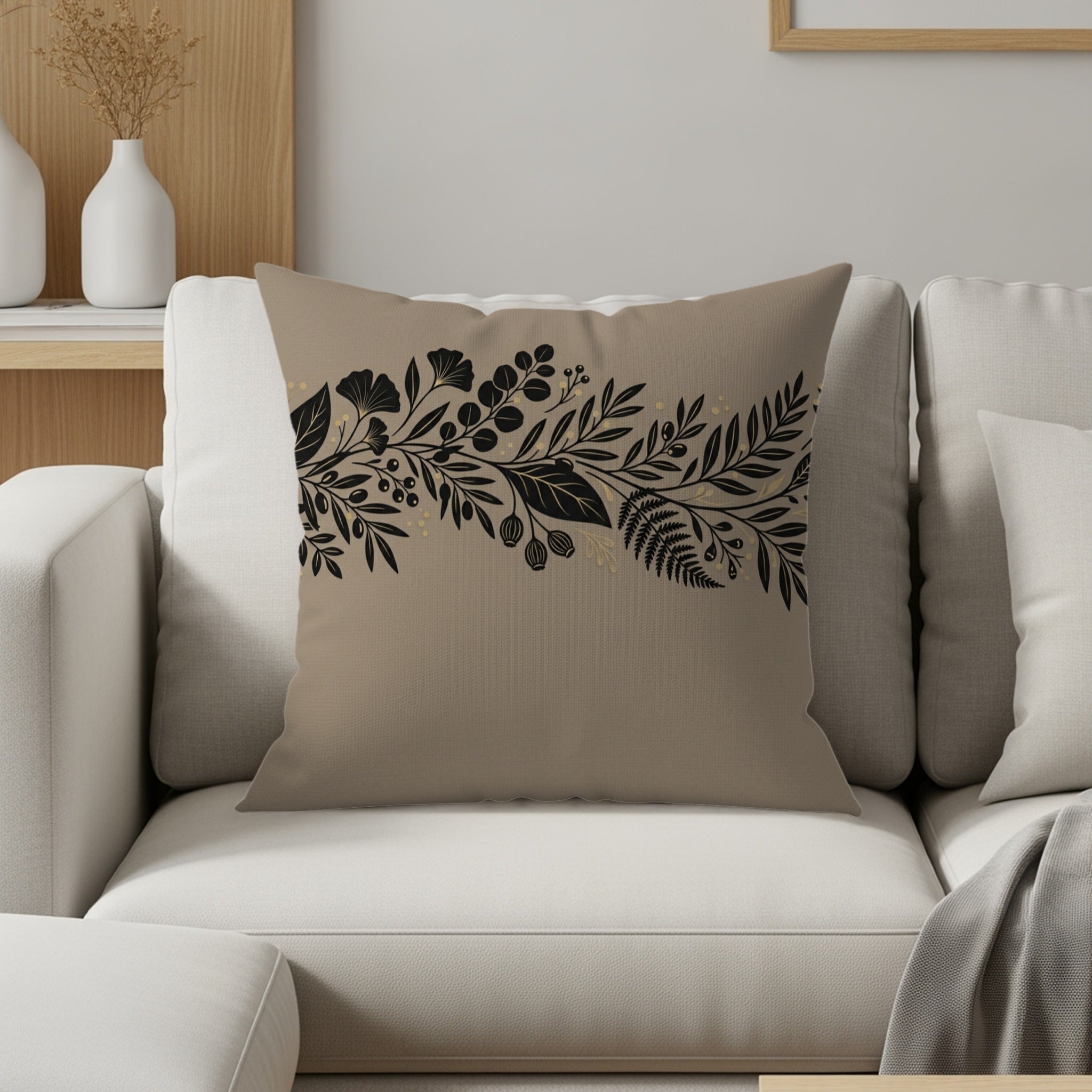 Tan throw pillow with black floral branch design on neutral couch.