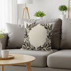 Decorative cream throw pillow with a dark leaf wreath design.