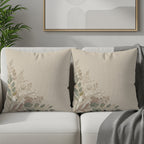 Two square throw pillows with botanical floral print on a sofa.