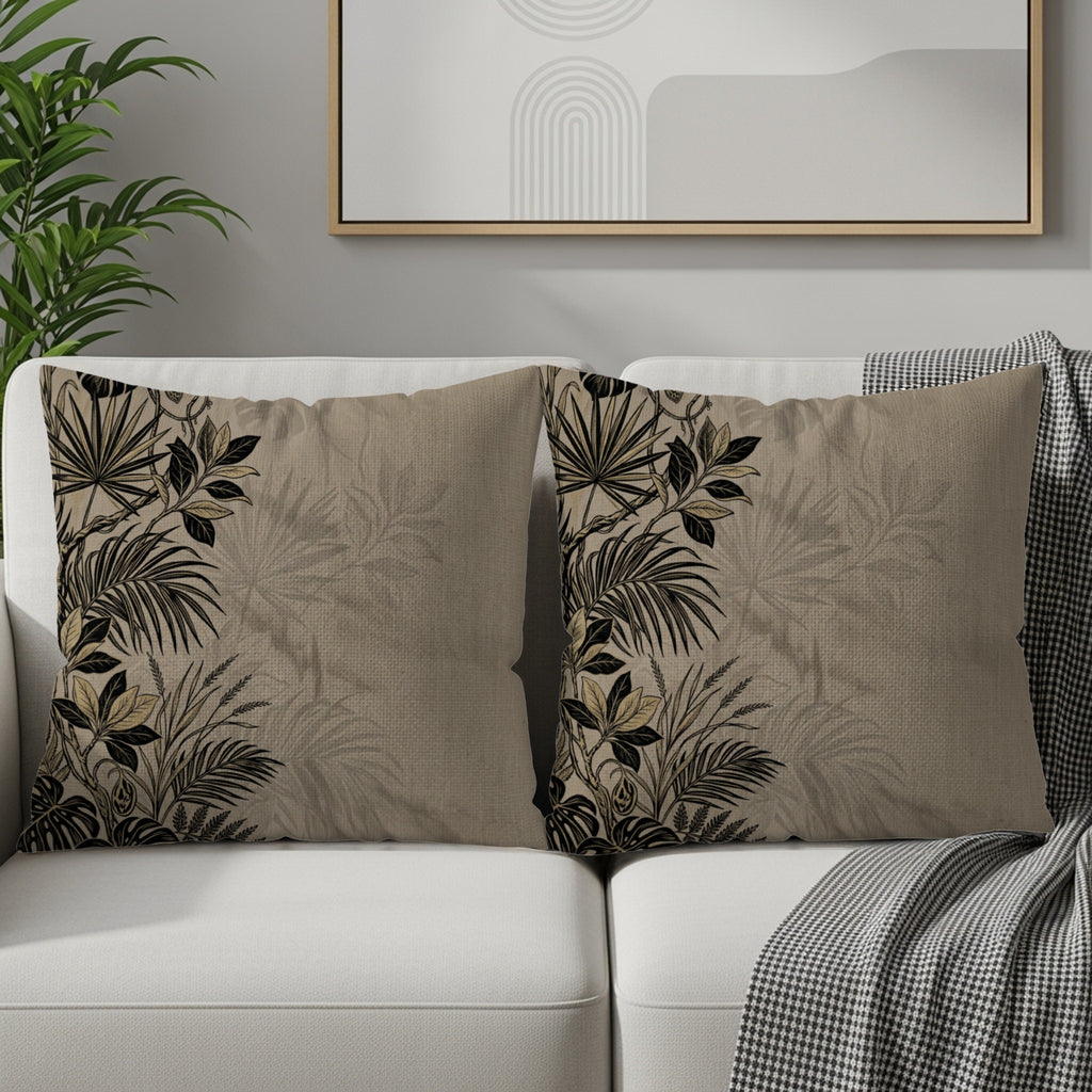 Two neutral throw pillows with dark botanical leaf print on a white sofa.