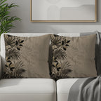 Two neutral throw pillows with dark botanical leaf print on a white sofa.