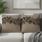 Tan throw pillows with black floral border design on a sofa.