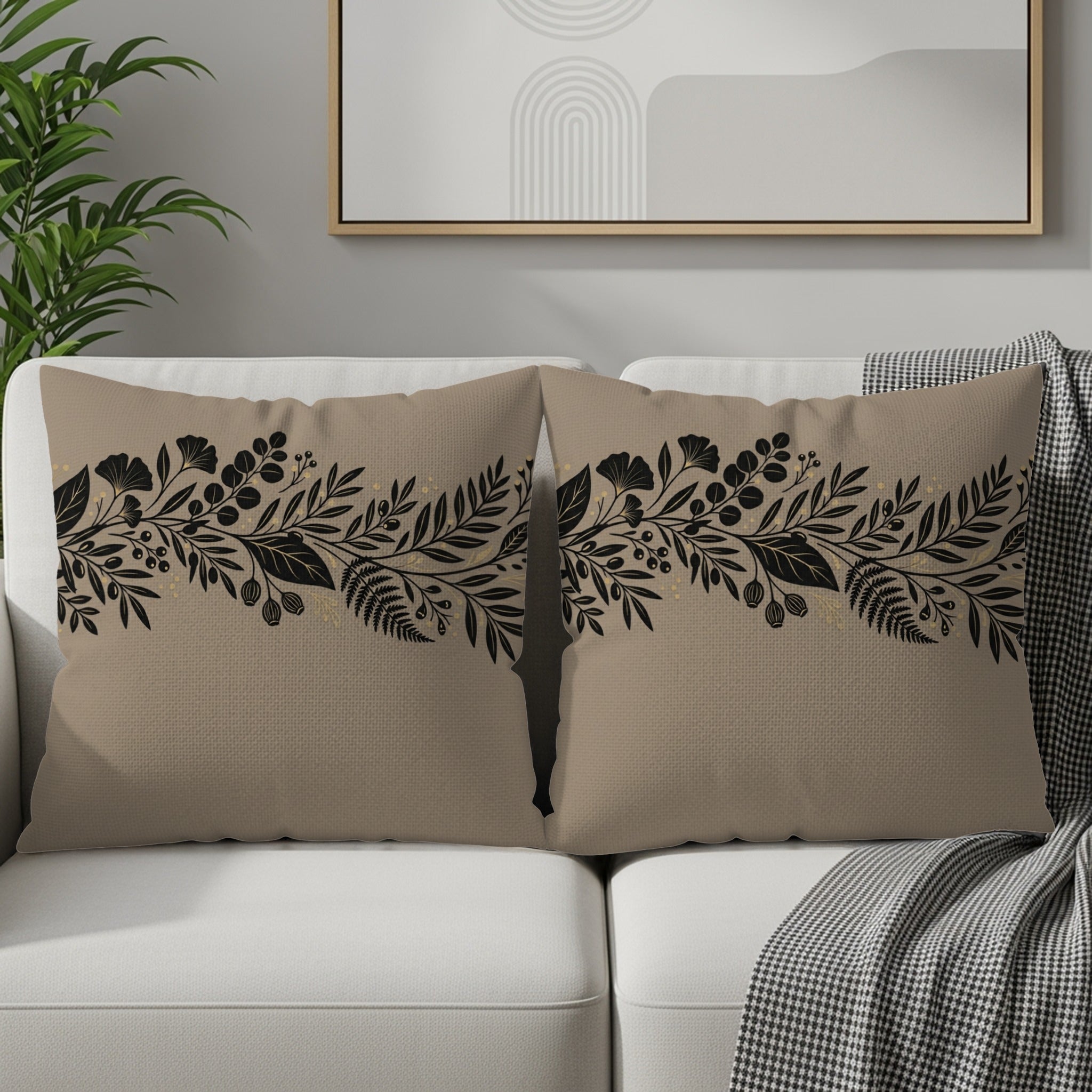 Tan throw pillows with black floral border design on a sofa.
