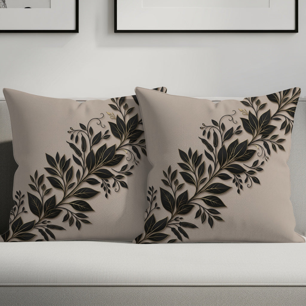Two beige throw pillows with black and gold floral vine design on a couch.