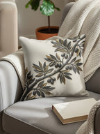 Embossed olive branch on a decorative throw pillow on a chair.