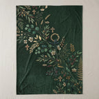 Dark green blanket with a gold floral and cross botanical design.