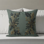 Green throw pillow with gold and dark green floral leaf design on a bed.