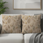 Two taupe throw pillows with a delicate botanical pattern on a cream sofa.
