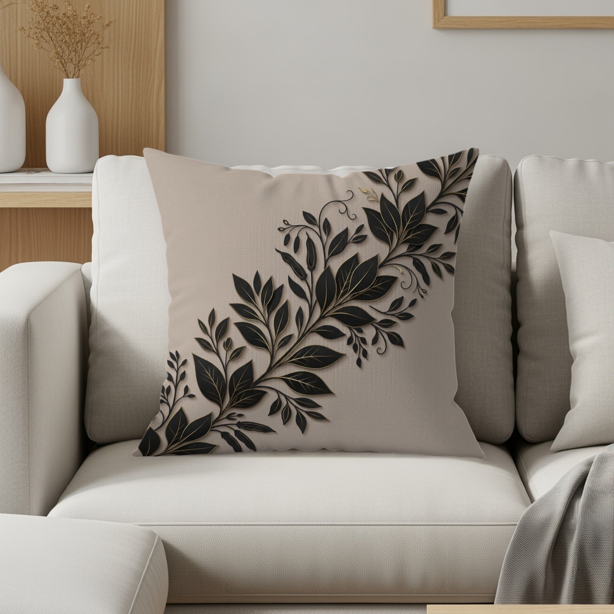 Beige decorative pillow with black floral vine design on a sofa.
