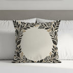 Square pillow with ornate black and gold floral border on a bed.