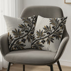 Two decorative throw pillows with an olive branch motif on a gray armchair.