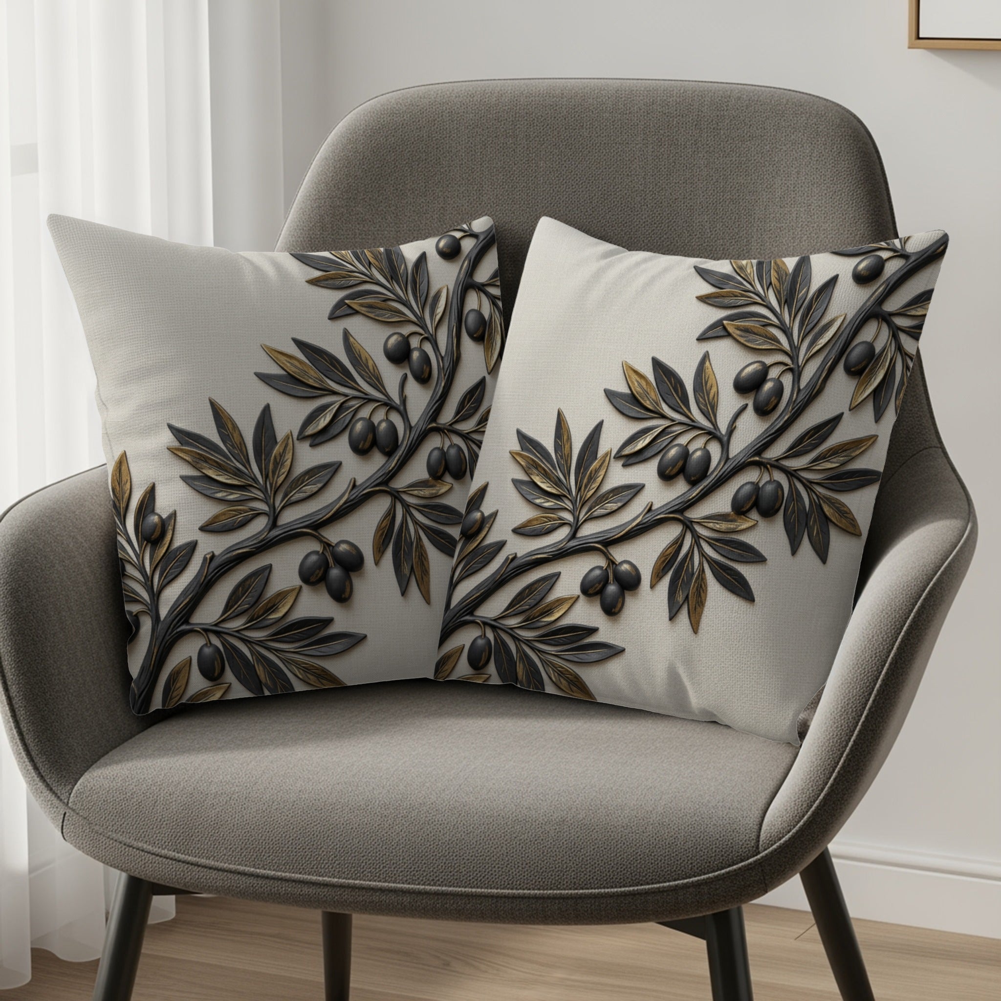Two decorative throw pillows with an olive branch motif on a gray armchair.