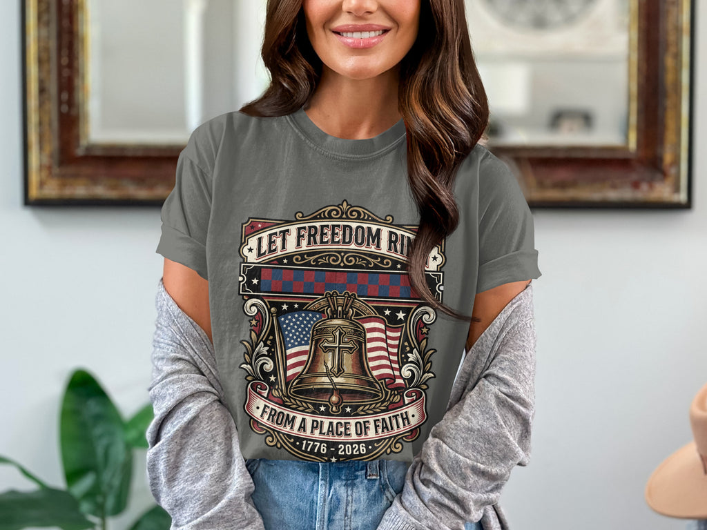 Grey t-shirt with Liberty Bell, American flag, and text "Let Freedom Ride from a Place of Faith 1776-2026".