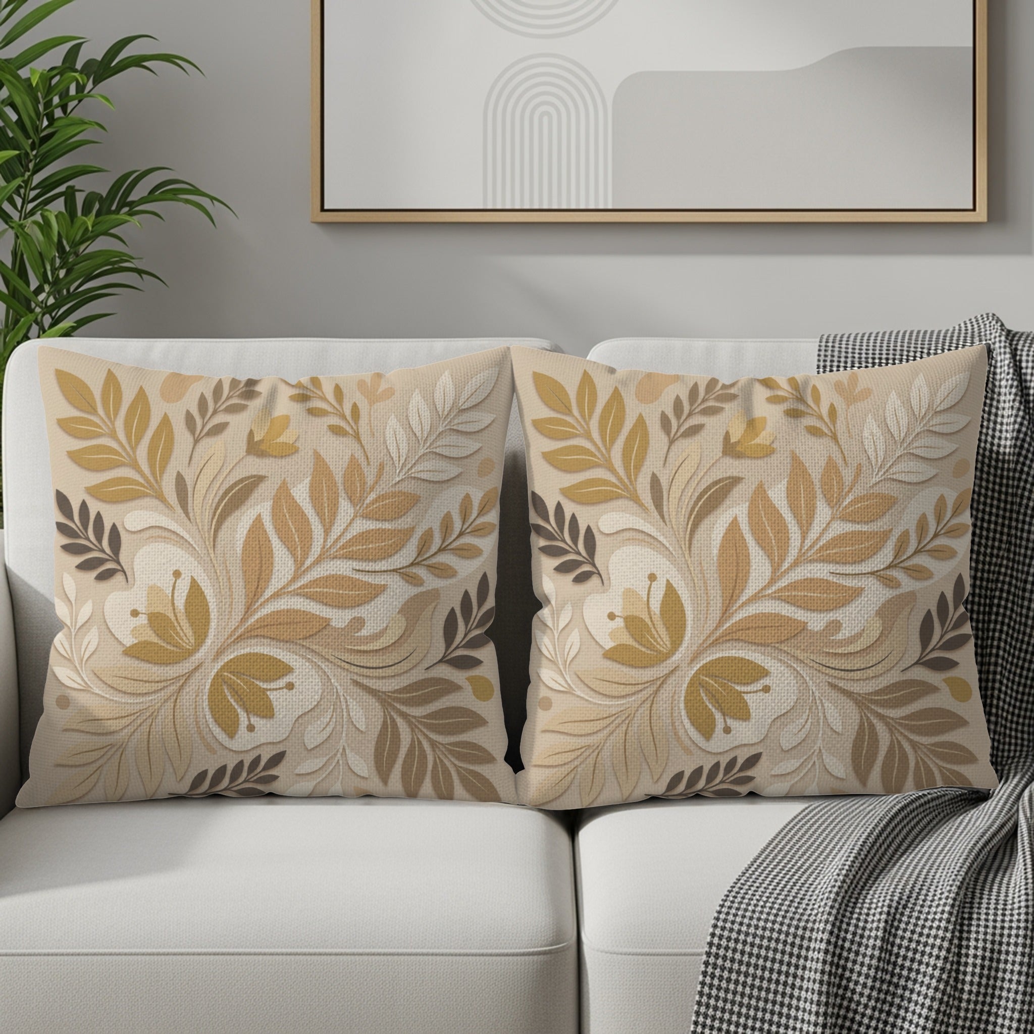 Two decorative throw pillows with a beige floral and leaf pattern on a couch.