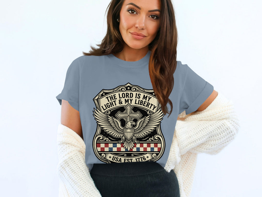 T-shirt with a crest featuring a cross, eagle, and "The Lord is my light & my liberty, USA Est 1776".
