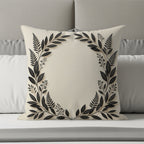 Cream pillow with black floral wreath design on a bed.