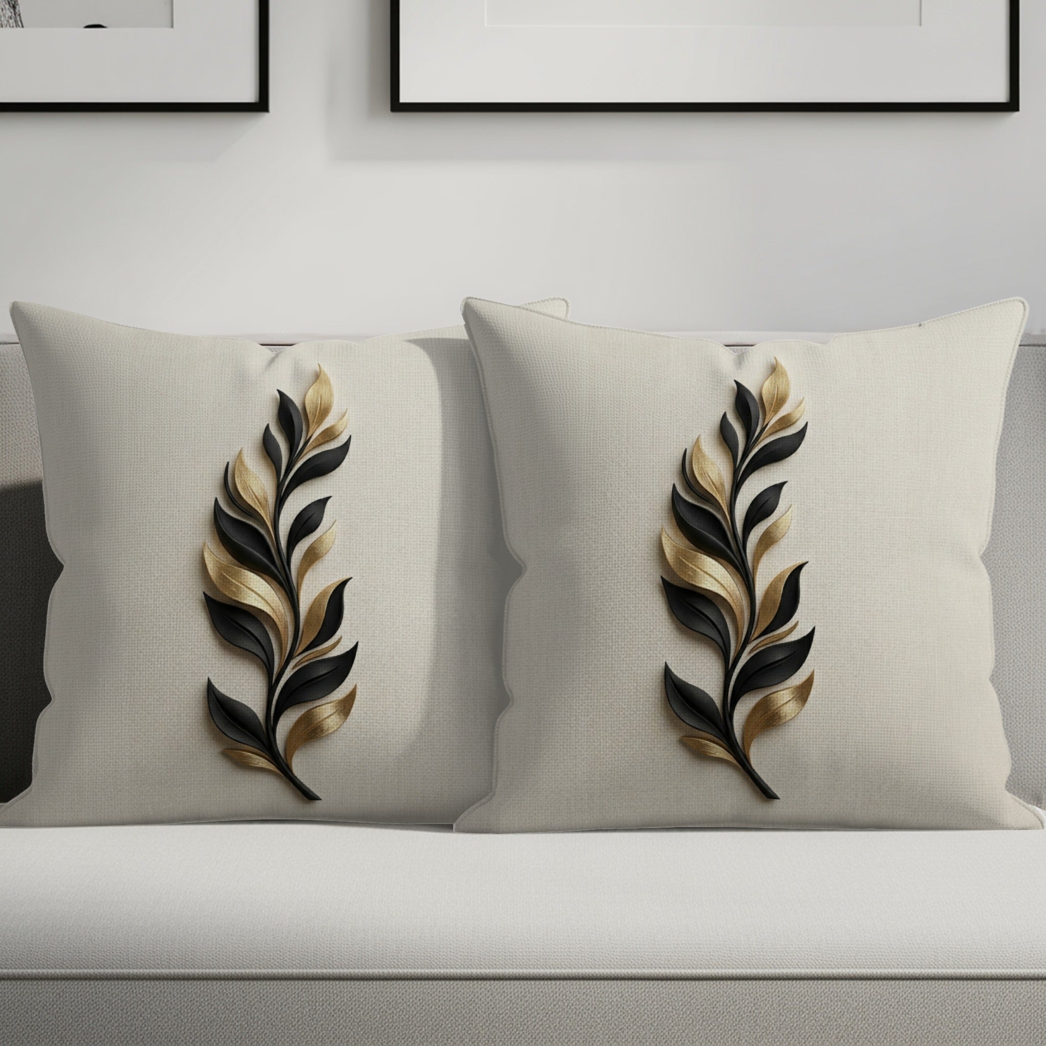 Two cream throw pillows with black and gold feather designs on a sofa.