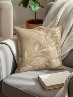 Tan throw pillow with intricate botanical design on a grey armchair.